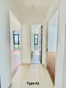 Bright hallway of a Type A1 apartment with white walls and a glossy tile floor; three doorways lead to living spaces, with a bathroom visible at the end.