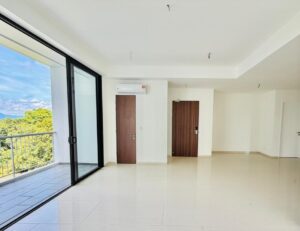 Bright, empty living room with large glass sliding doors to a balcony and a view of trees and sky outside. Two wooden doors along the back wall; wall-mounted air conditioner above one door; ceiling wires for lights visible.