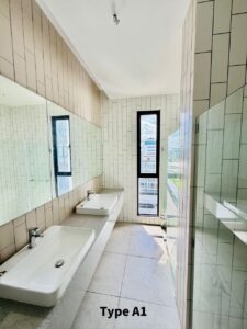 Modern bathroom with double sinks on a light countertop, white tile walls, a tall narrow window, and a glass shower. 'Type A1' text visible on the floor.