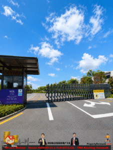 Retractable security gate blocks a driveway, with a guard booth on the left and a no trespassing sign.
