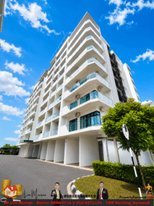White modern apartment building with glass balconies against a bright blue sky.