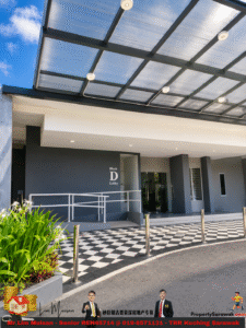 Modern building entrance with glass doors labeled Block D Lobby under a white overhang and a transparent canopy above.