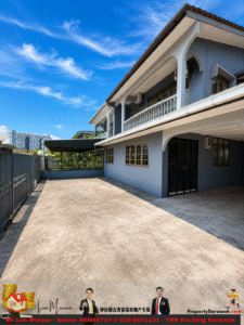 Two-story blue building with white arches and a balcony, gated entrance, and a wide concrete driveway under a bright blue sky.