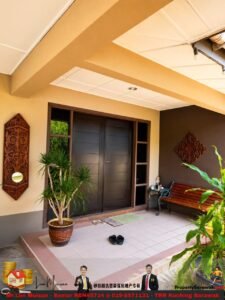 Covered entry porch with dark double doors, beige walls, and a large potted plant; a wooden bench and decorative wall art on the right.