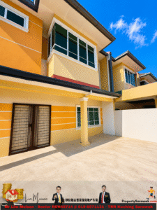 Exterior of a modern yellow townhouse with orange accents, large white-trimmed windows, green glass, a metal gate door, and a concrete driveway under a bright blue sky.