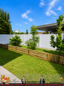 Sunny backyard with green lawn, small trees, a bamboo border, and a white privacy fence under a blue sky.