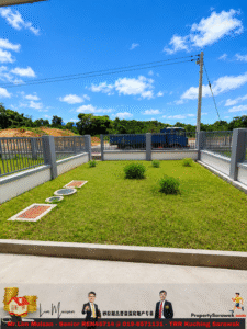 Green grassy yard enclosed by a gray railing, with a blue truck in the background and power lines against a clear blue sky.