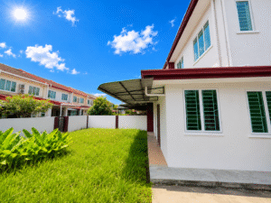 White two-story residential buildings with red trim facing a grassy courtyard under a bright blue sky with a sun glare and puffy clouds.