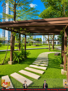 Sunny courtyard with a curved stone path under a brown pergola, green grass and trees, with modern apartment buildings in the background.