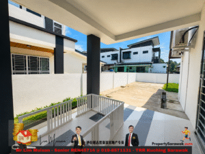 Outdoor covered patio of a modern white-and-gray house, black columns, and a paved yard with neighboring homes in the background.