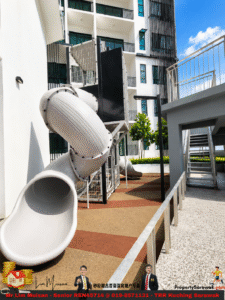 White tubular slide structure in a modern residential courtyard with balconies and blue sky above.