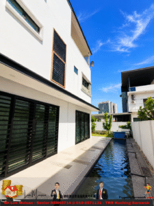 Modern white multi‑story house with large black-framed glass doors beside a narrow pool under a bright blue sky.