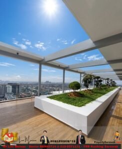 Rooftop terrace with a long white planter bed of greenery, wooden deck, and a glass railing overlooking a city skyline under a bright sunny sky.