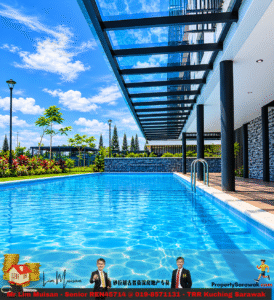Outdoor resort pool beside a modern glass-covered walkway, blue sky, and landscaped greenery in the background.
