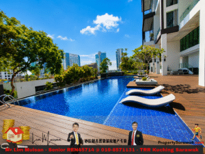 Rooftop pool beside a modern white apartment building, with a wooden deck, white lounge chairs, and a city skyline in the background.