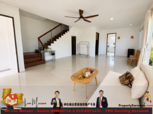 Bright open living room with white walls, tiled floor, and a wooden staircase along the left wall; ceiling fan overhead and large windows on the right.