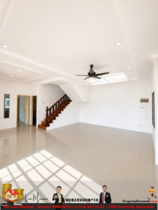 Bright, empty living room with white walls, glossy tiled floor, a dark wooden staircase, and a ceiling fan; sunlight casts shadows through windows.