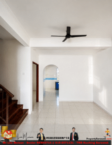 Bright living room with white walls, wooden staircase on the left, and a black ceiling fan overhead; an arched doorway leads to a tiled kitchen.