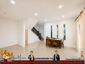 Bright open living and dining space with a wooden staircase on the left, glass-top dining table and six wooden chairs, white walls, and tall narrow windows on the far wall.