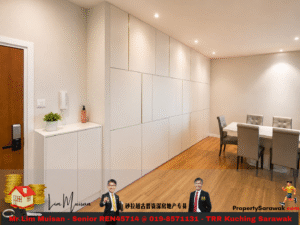 Minimalist dining area with a long wall of white storage cabinets, a white table and gray upholstered chairs, and wood flooring.