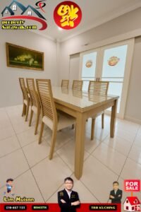 Showroom dining room with a glass-top wooden table and eight slatted chairs, a fruit still-life painting on the wall, and real estate branding in the corner of the image.