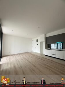 Bright, unfurnished open-plan living area with light wood flooring and a modern white-and-gray kitchen along the right side.