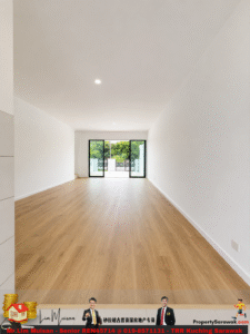 Bright, empty living room with light wood flooring and large glass doors opening to a green outdoor space .