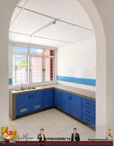 U-shaped kitchen with blue lower cabinets, beige countertops, white tiled walls with a blue stripe, and a large window with bars above the sink.