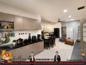 Open-plan kitchen and living area: grey cabinets, black countertop, dining table, and a seating area in the background.