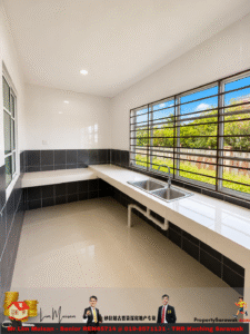 Bright kitchen with a long white countertop, double sink under a large window showing green outdoor view and a black-tiled backsplash.