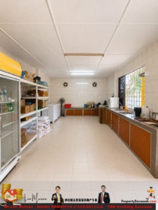 Commercial kitchen/pantry with white tiled walls, long brown cabinets, and metal shelves stocked with boxes and bags on the left and appliances along the right wall.
