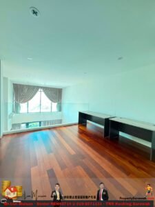 Empty office/ studio with a large window and beige curtains, two long desks along the right wall, and warm wooden floor.