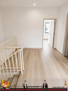 Bright upstairs landing with light wood flooring, white railing on the left, and an open doorway leading to a room with a window in the background.