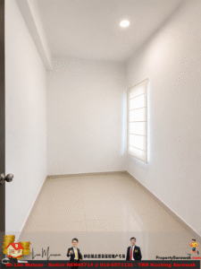 Small, empty rectangular room with white walls, beige tiled floor, a window with a blind on the right, and a ceiling light; door with knob on the left.