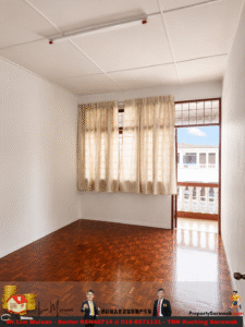 A small empty room with white walls, parquet floor, beige curtains over a large window, and a door to a balcony showing a building exterior.