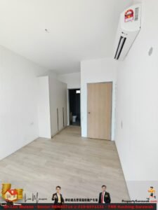 Empty white bedroom with light wood floor, built-in wardrobe, wooden door, and wall-mounted air conditioner. A doorway reveals a bathroom in the back.