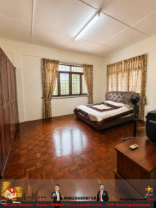 Bedroom with a tufted brown bed, beige quilt, and a standing fan near the windowed wall; wooden wardrobe on the left; parquet floor.