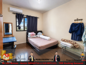 Cozy bedroom with a low bed, pink sheets, and stacked pillows under blue curtains by a window; desk and mirror on the left, clothes rack on the right.