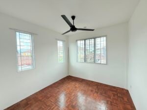 Empty small room with white walls, parquet floor, three metal-bar windows, and a black ceiling fan.