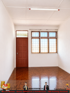 Empty interior room with white walls, a parquet floor, a brown paneled door on the left, and a large multi‑pane window on the right letting in daylight.