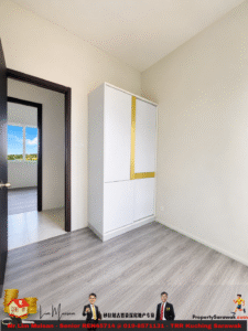 Empty room with light gray wood floor, white walls, and a tall white cabinet with a yellow trim, near an open doorway to a sunlit room.