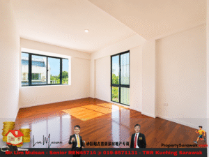 Bright empty room with white walls, polished wooden floor, and large windows showing greenery outside.