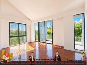 Sunlit empty living room with large glass doors and a balcony, warm wooden floors, and a view of greenery outside (security bars visible on the left window).