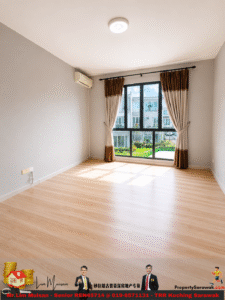 Bright, empty room with light wood flooring, gray walls, and a large window framed by brown and cream curtains letting in sunlight.