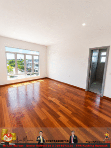 Bright empty room with white walls, large window letting in sunlight, and a door to a tiled bathroom; polished hardwood floor visible throughout.