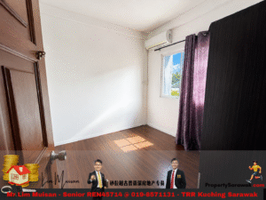 Empty small bedroom with white walls, dark hardwood floor, a window with a purple curtain, and a dark wardrobe; door partly open on the left.