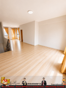 Bright unfurnished living area with light wood flooring, white walls, large windows with yellow curtains, and a staircase railing to the left.