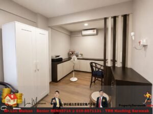 Modern home office with white wardrobe, dark wood cabinetry, a standing fan, and a desk area separated by vertical slats in a neutral room.