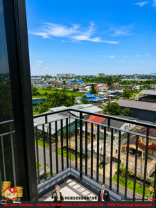 View from a balcony: a suburban neighborhood with colorful houses, palm trees, and a clear blue sky.
