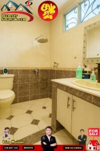 Bathroom with beige tiled walls and floor, toilet, wall-mounted shower, and a sink with countertop; window with decorative grille; property ad graphics and agent photos along the edges.